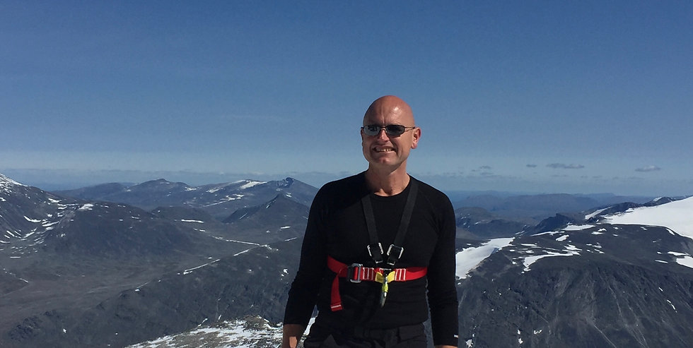 Jørn Eikanger på en fjelltopp med utsikt over snødekte fjell
